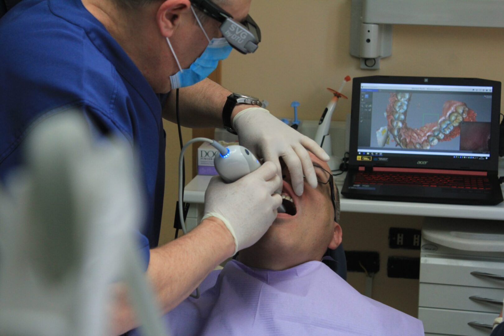 Dentist Examining Patient With Latest Equipment and Watch on Laptop